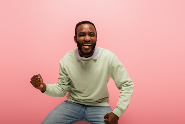 Souriant homme afro-américain montrant un geste oui isolé sur rose  - Photo, image
