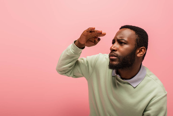 Afrykański Amerykanin w swetrze odwraca wzrok odizolowany na różowy  - Zdjęcie, obraz