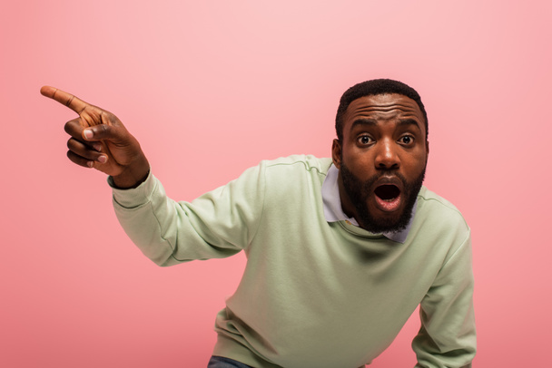 Amazed african american man pointing away isolated on pink  - Photo, Image
