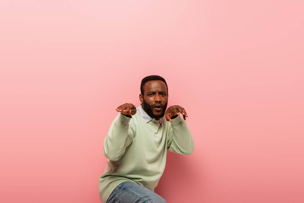 Young african american man gesturing on pink background  - Φωτογραφία, εικόνα