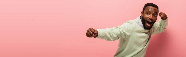 Screaming african american man holding hands in fists on pink background, banner  - Φωτογραφία, εικόνα
