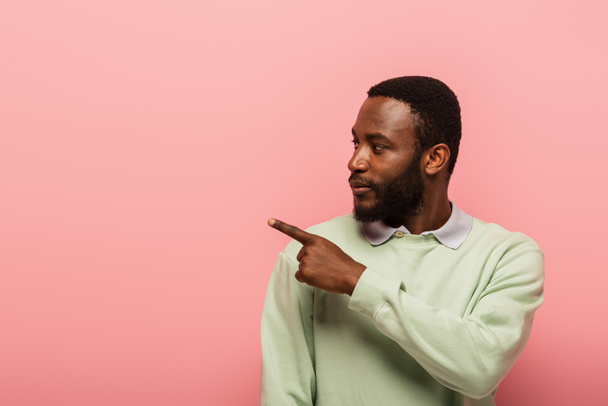 African american man in jumper pointing away with finger isolated on pink  - Foto, Bild