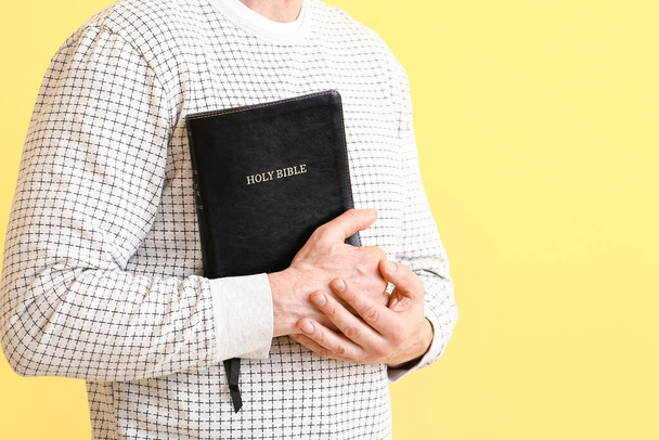 Людина з Біблією на кольоровому фоні, крупним планом
 - Фото, зображення