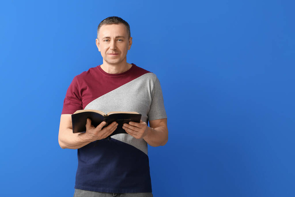 Man with Bible on color background - Photo, Image