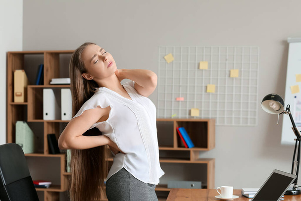 Молодая женщина страдает от болей в спине в офисе - Фото, изображение