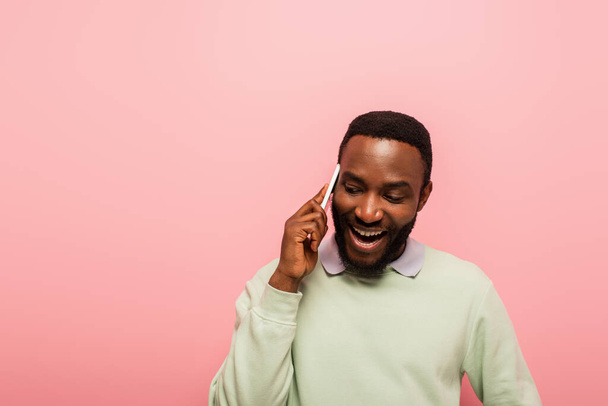 Usmívající se africký Američan mluví na mobilním telefonu izolované na růžové  - Fotografie, Obrázek