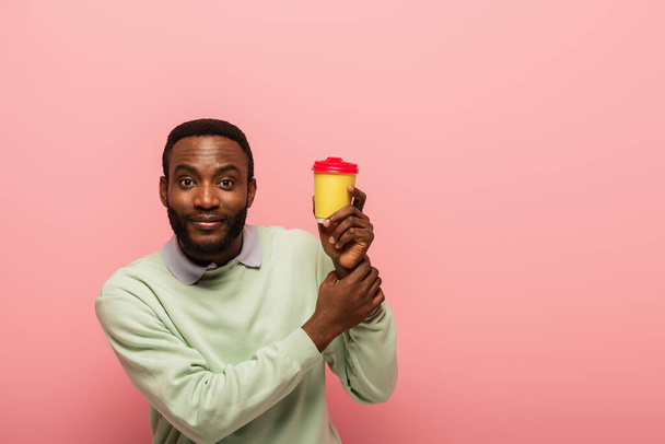 African american man with coffee to go looking at camera isolated on pink  - Fotoğraf, Görsel