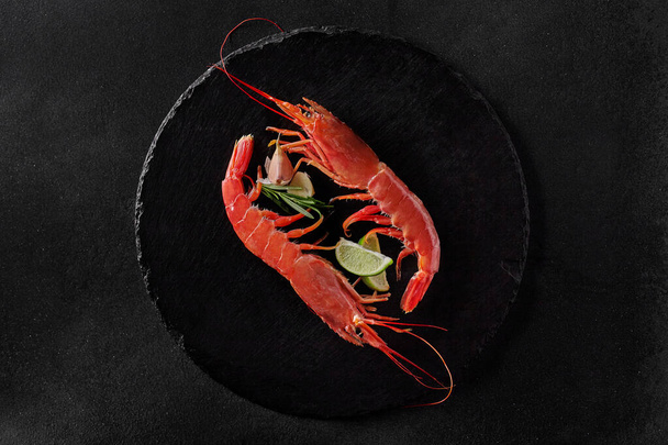 Top view of two shrimps with condiments on round slate board - Foto, Imagem