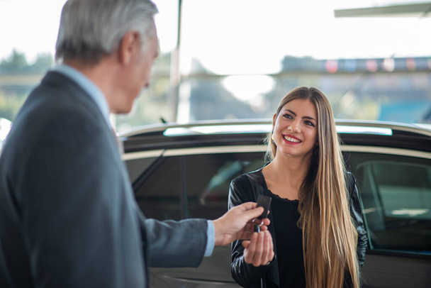 Young woman taking the keys for her car in a showroom - Φωτογραφία, εικόνα