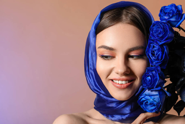 Stylish young woman with blue roses on color background - Foto, Imagen