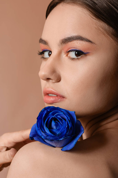 Beautiful young woman with blue rose on color background, closeup - Foto, imagen