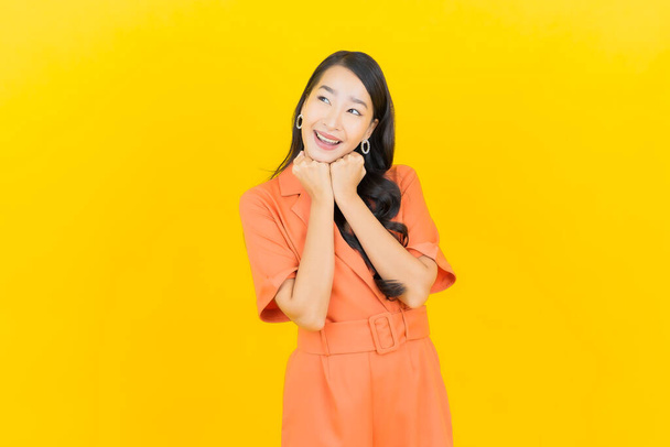 Retrato bonito jovem asiático mulher sorriso com ação na cor amarela fundo - Foto, Imagem