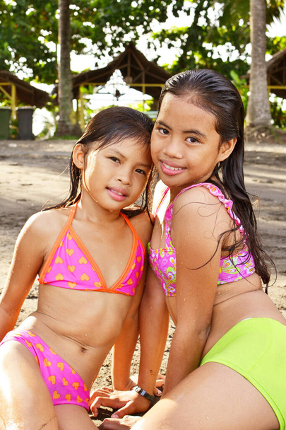 Un primer plano de dos jóvenes hermanas asiáticas disfrutando de la playa tropical - Foto, imagen