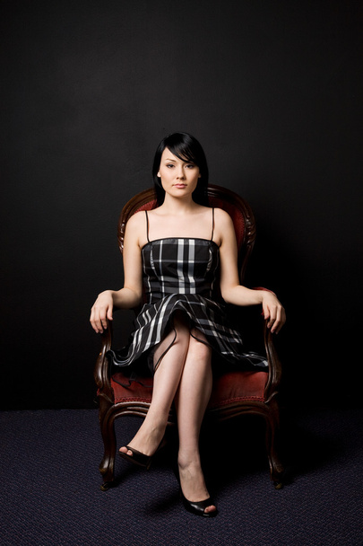 Модный снимок красивой женщины, сидящей на винтажном стуле
 - Фото, изображение