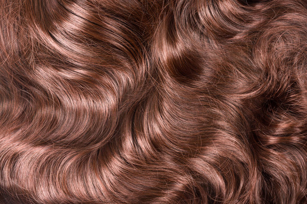 Brown hair texture. Wavy long curly light brown hair close up as background. Hair extensions, materials and cosmetics, hair care. Hairstyle, haircut or dying in salon - Fotoğraf, Görsel