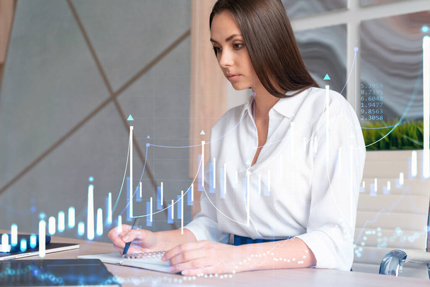Portrait of attractive businesswoman in formal wear working with documents and thinking how to optimize trading strategy at corporate finance fund. Forex chart hologram over modern office background - Foto, afbeelding