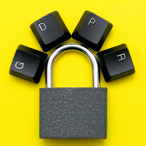 Закрытый железный замок на желтом фоне на рычаге блокировки выкладываются клавиши клавиатуры компьютера с аббревиатурой GDPR concept personal data protection. Высокое качество фото - Фото, изображение