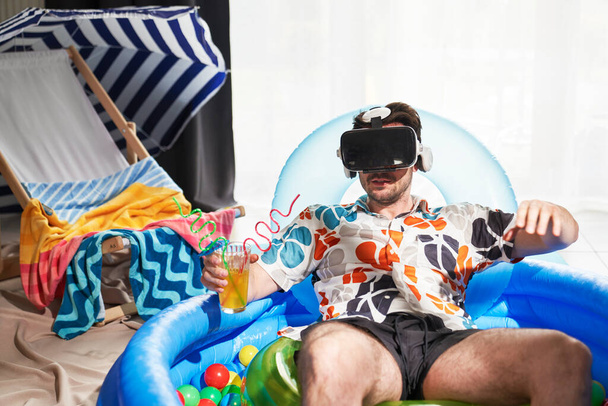 Man with VR glasses sitting in an inflatable ball pool                                - Photo, image