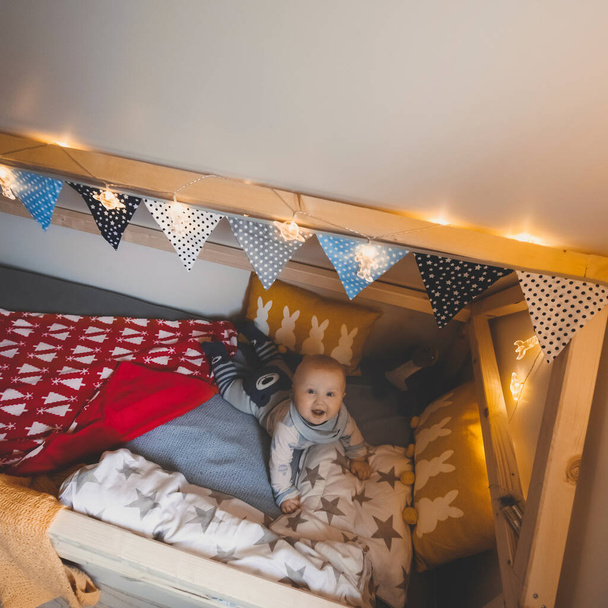 Portrait of cute baby boy in his house bed. Happy childhood - Φωτογραφία, εικόνα