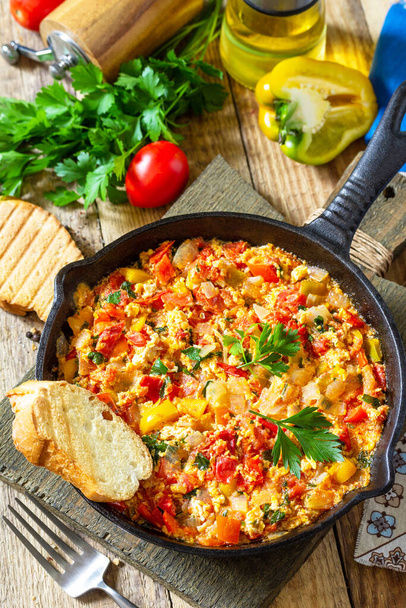 Traditional Turkish dish. Mememen (fried vegetables with scrambled egg) in a cast iron frying pan on a wooden table. - Photo, Image