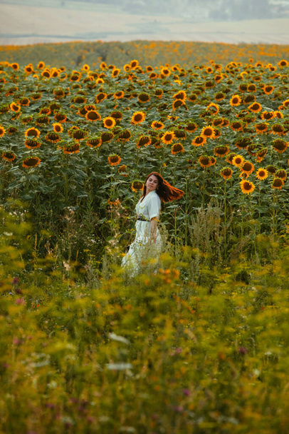 fiatal gyönyörű nő a napraforgó mezőn naplementekor. életmódbeli tevékenységek - Fotó, kép