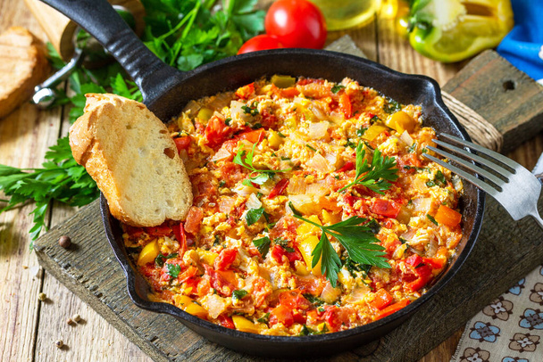 Traditional Turkish dish. Mememen (fried vegetables with scrambled egg) in a cast iron frying pan on a wooden table. - Photo, Image