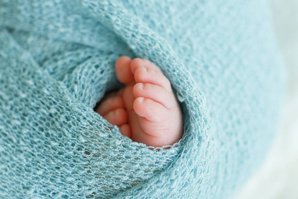 Dos lindos pequeños pies de bebé envueltos en una manta de punto azul-verde aqua - Foto, Imagen