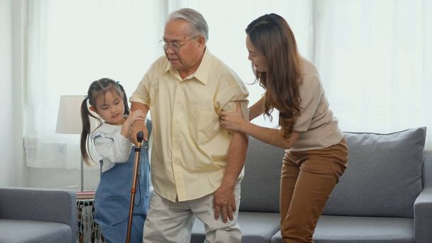 Asian family, Daughter and granddaughter take care support grandfather who is suffering from knee pain Got walking outside to take a walk And grandpa with a stick, elderly health care concept - Photo, Image