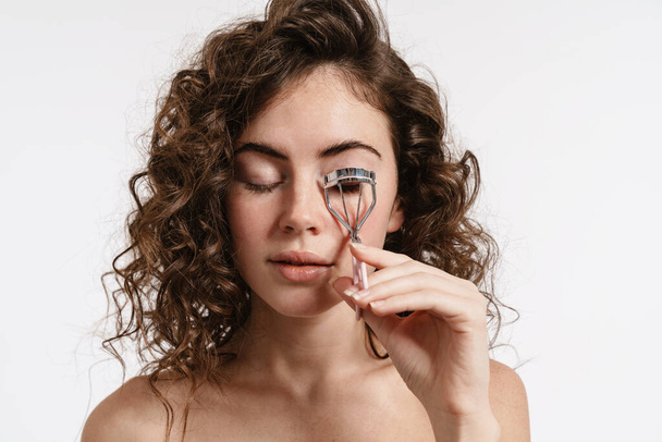 Beautiful shirtless curly girl using eyelashes curler isolated over white background - Foto, imagen