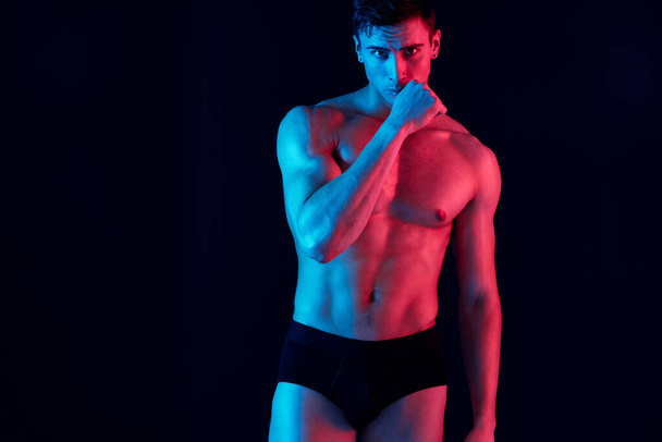 Seksi erkek sporcu elleri siyah bir arka plan ve neon renkli bir model üzerinde hareket ediyor. - Fotoğraf, Görsel