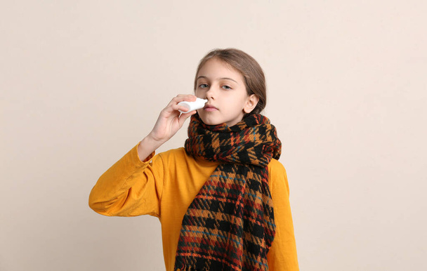 Sick little girl using nasal spray on beige background - Foto, Imagem