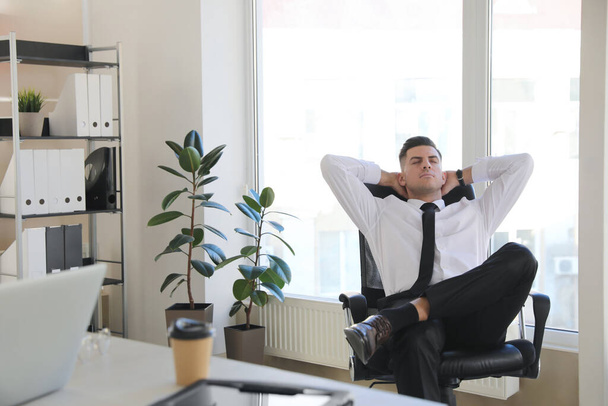 Businessman relaxing in office chair at workplace - Valokuva, kuva