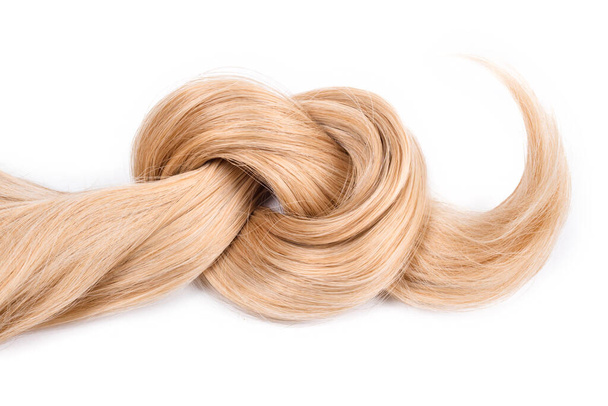 Blonde hair lock tied in knot. Strand of honey blonde hair isolated on white background, top view. Hairdresser service, hair strength, haircut, dying or coloring, hair extension, treatment concept - 写真・画像