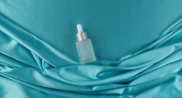 hydrating facial serum and body on abstract background luxury cloth or wavy folds of silk texture satin velvet material, top view. The concept of organic, natural cosmetics - Photo, Image
