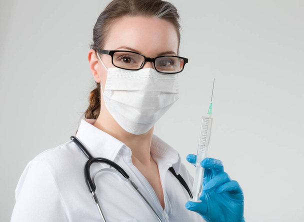 žena lékař nebo zdravotní sestra s obličejovou maskou a rukavicemi s nataženou injekční stříkačkou  - Fotografie, Obrázek