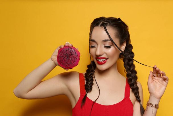 Young woman with fresh pitahaya on yellow background. Exotic fruit - Foto, afbeelding