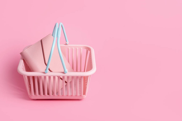Colorful plastic shopping basket with leather wallet. Empty pink and blue supermarket basket on pink pastel background. Creative design, shopping, black friday, discount, advertising, sale concept - 写真・画像