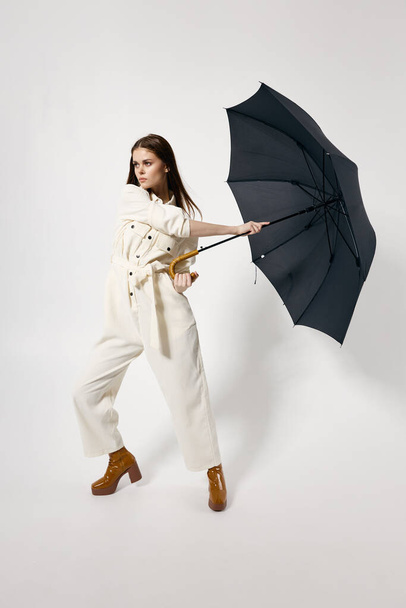 woman in overalls brown boots fashion open umbrella rain protection - Foto, afbeelding