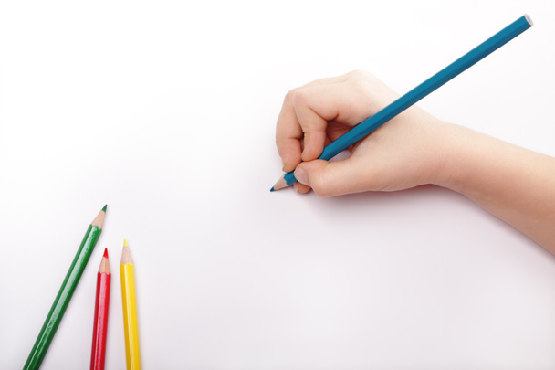 Child hand draws a blue pencil. White-gray background Above view. - Photo, Image