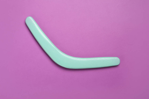 Turquoise wooden boomerang on purple background, top view - Fotografie, Obrázek