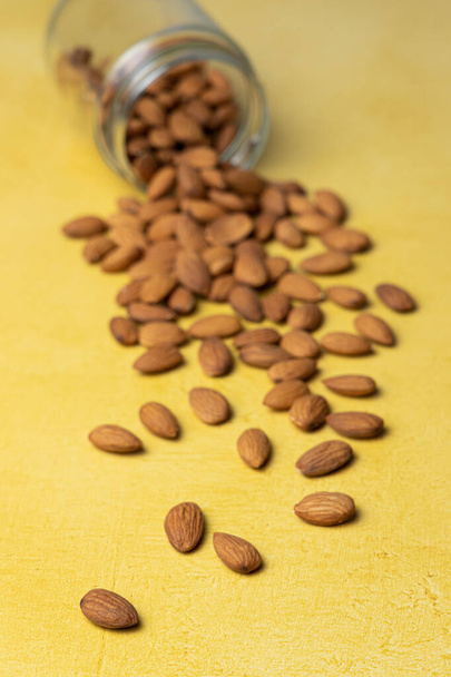 Pile of peeled raw almonds on a yellow table - Фото, зображення