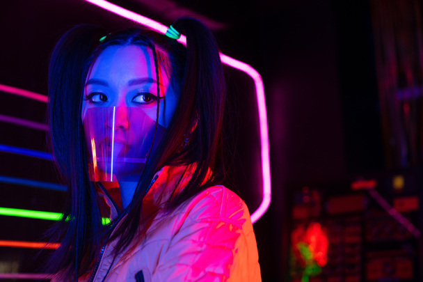 young asian woman in face shield near neon lighting  - Photo, image