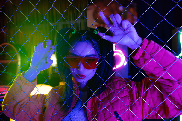 stylish young asian woman in sunglasses near metallic fence  - Zdjęcie, obraz