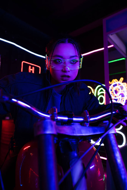 young asian woman in sunglasses riding motorbike near neon sign  - Photo, Image