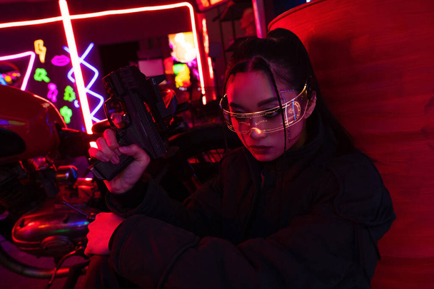 озброєна азіатка в сонцезахисних окулярах тримає пістолет
  - Фото, зображення