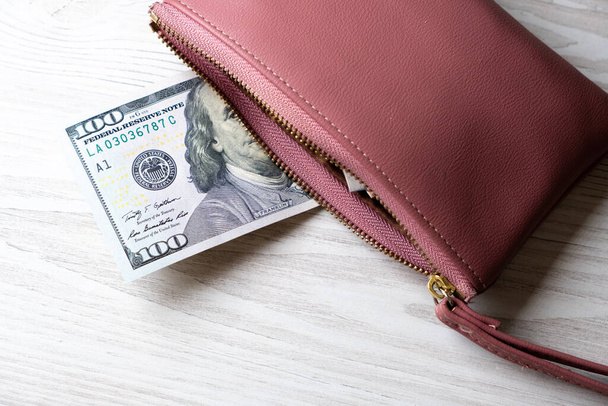 розовый бумажник со стодолларовой купюрой и кучей денег. Финансы, расходы и концепция доходов  - Фото, изображение