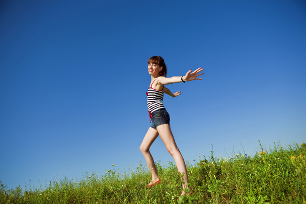 Happy young woman jumping in a field - Valokuva, kuva