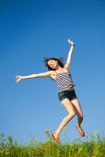Onnellinen nuori nainen hyppii pellolla
 - Valokuva, kuva