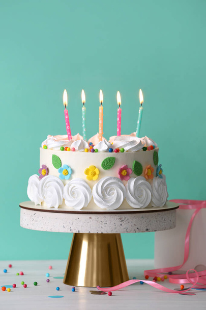 Delicious birthday cake and party decor on white wooden table against turquoise background - Φωτογραφία, εικόνα