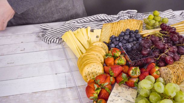 Paso a paso. Organizar bandeja de queso con frutas frescas, queso gourmet y galletas saladas. - Foto, imagen